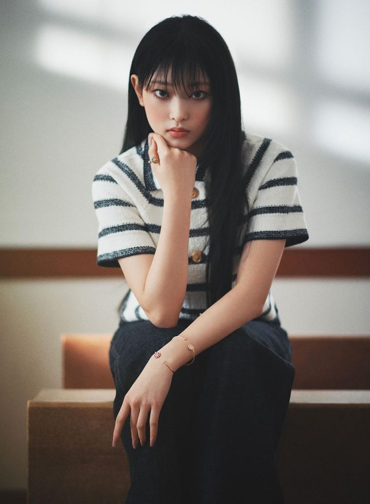 La chanteuse de NewJeans haerin pour sa première campagne avec Dior, en avril 2023, avec un pull à manche courte rayé blanc et bleu, et des bijoux en or rose.