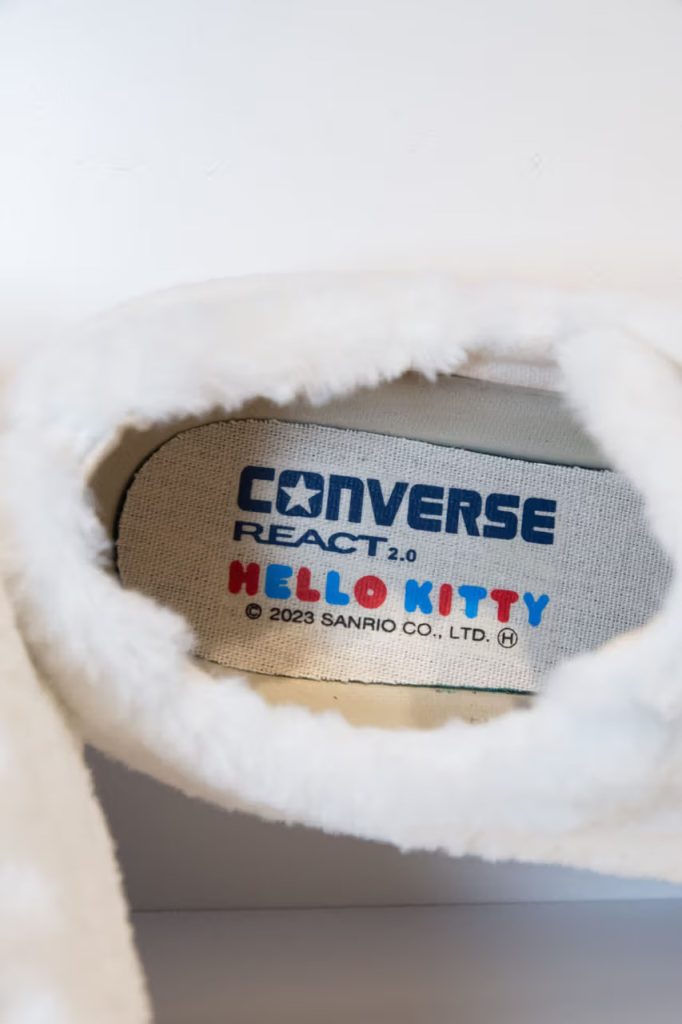 L'intérieur de la Converse All Star basse avec de la moumoute blanche et un noeud rouge Hello Kitty, en 2023